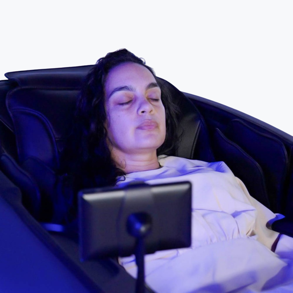 Person relaxing in Floridian Brand Rebel 4D Massage Chair using the built-in adjustable tablet phone holder attachment