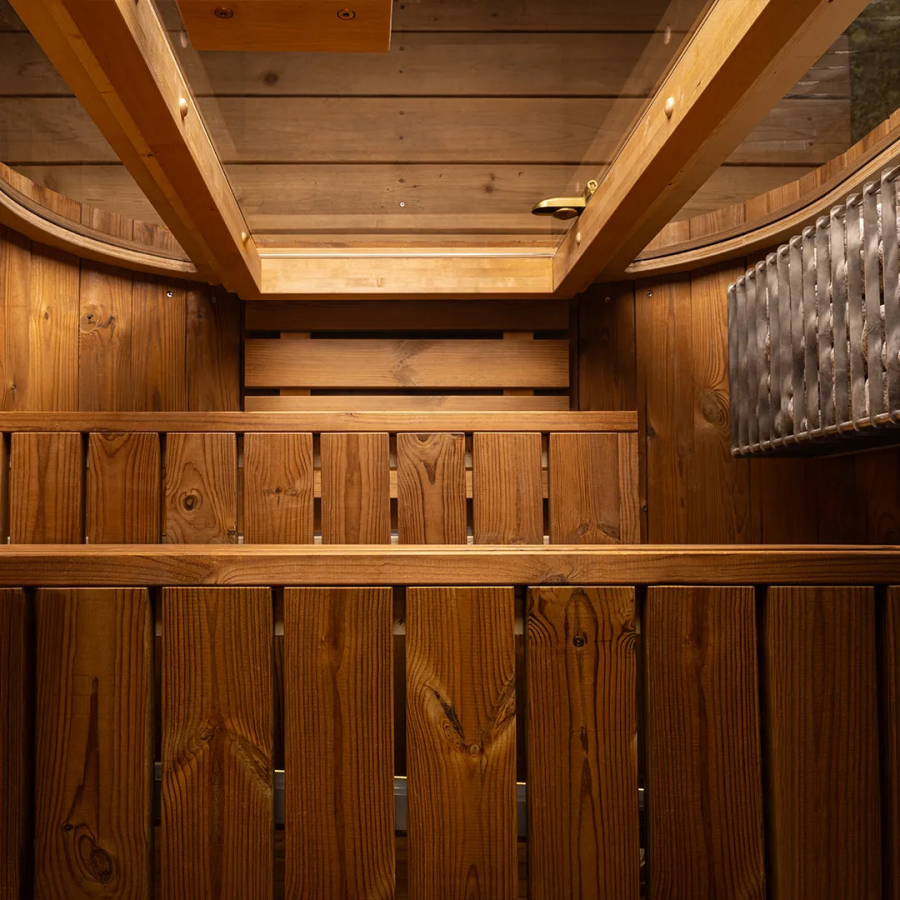 Auris One Luxury Outdoor Cedar Sauna interior showing cedar benches sauna heater with stones LED ceiling panel and warm lighting