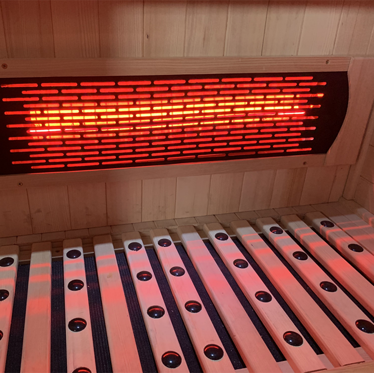 Lumin Three Indoor Infrared Sauna close-up of glowing full-spectrum infrared heating element with cedar bench slats in foreground