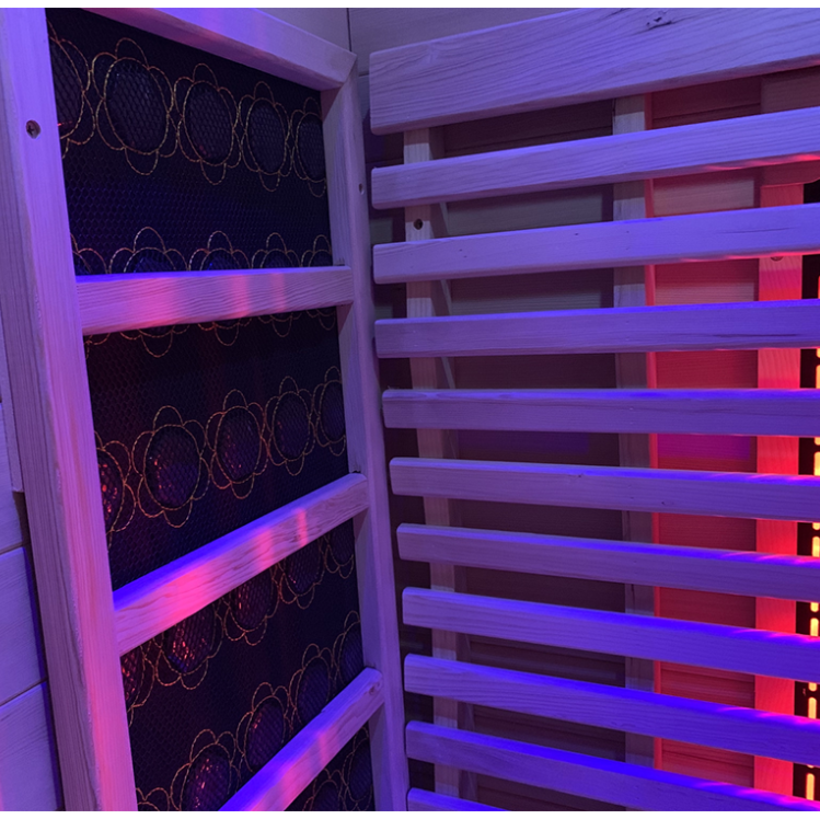 Lumin Two Indoor Infrared Sauna interior showing purple chromotherapy LED lighting cedar bench slats and glowing carbon far-infrared heater panels