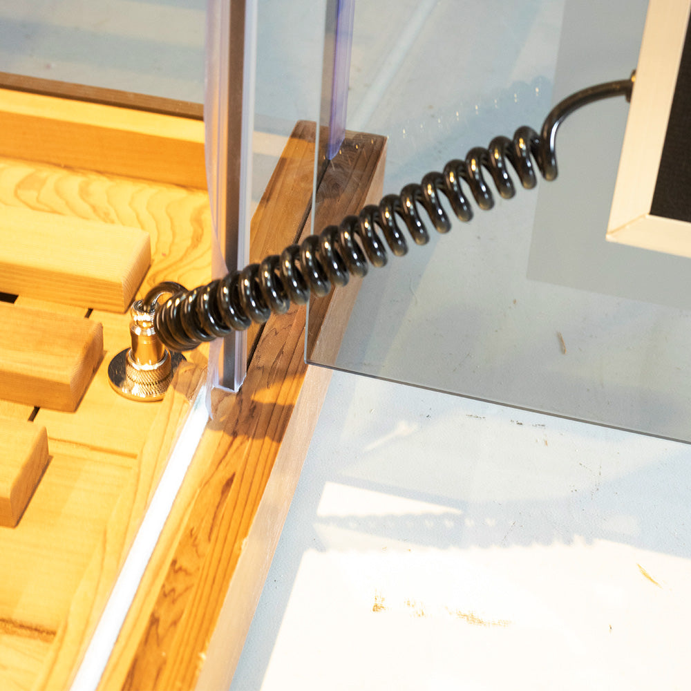 WizziSaunas SR01 Red Cedar Infrared Sauna close-up of glass door coiled spring tension closer attached to cedar wood door frame with brass anchor fitting