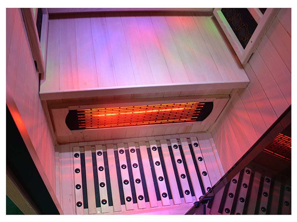 Lumin One Infrared Sauna interior close-up showing carbon infrared floor heater glowing orange-red under bench white wood walls and floor mat with purple chromotherapy lighting